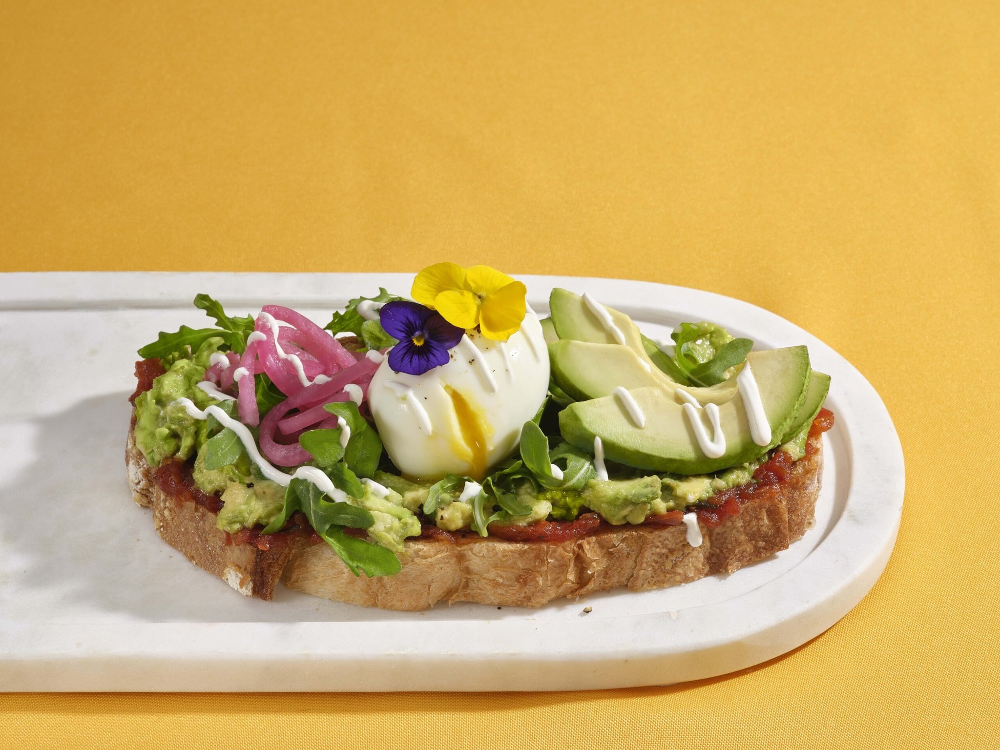 Brunch avocado toast topped with a runny open egg