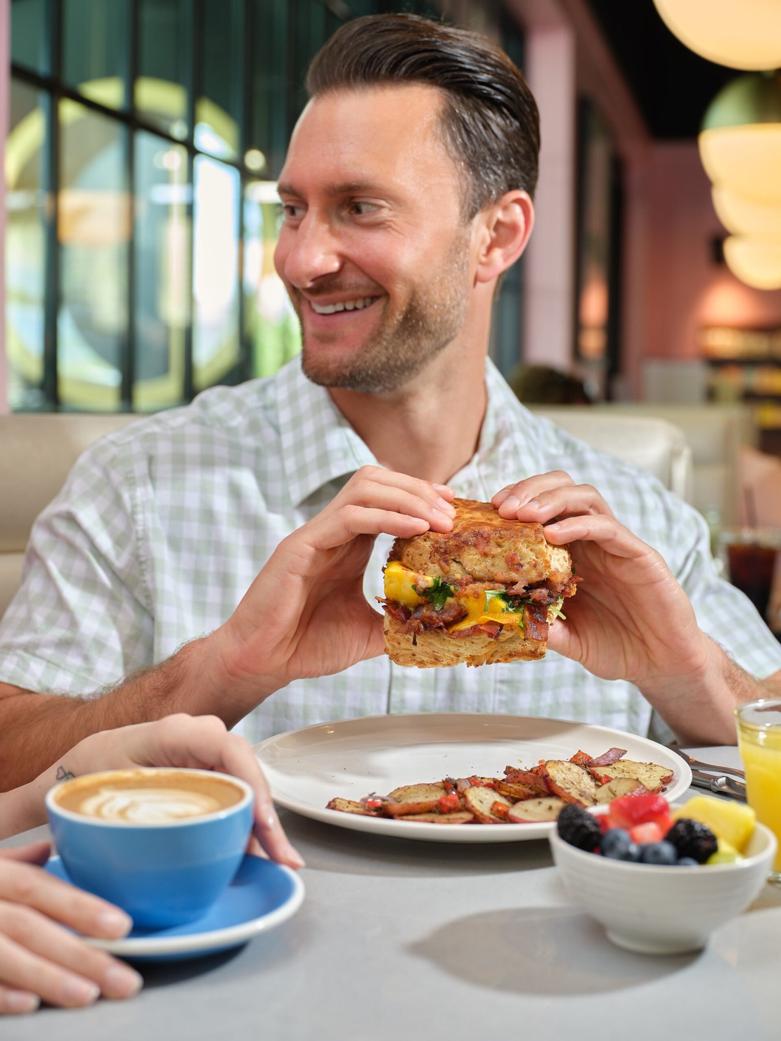 Male enjoying a cheddar biscuit sandwich at The Glass Knife Orlando Avenue location.